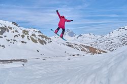 Unrecognizable snowboarder jumping on slope