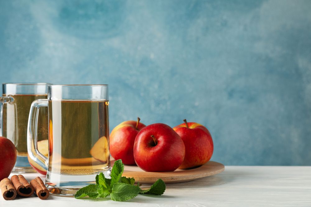 Composition with cider, cinnamon and apples on wooden background