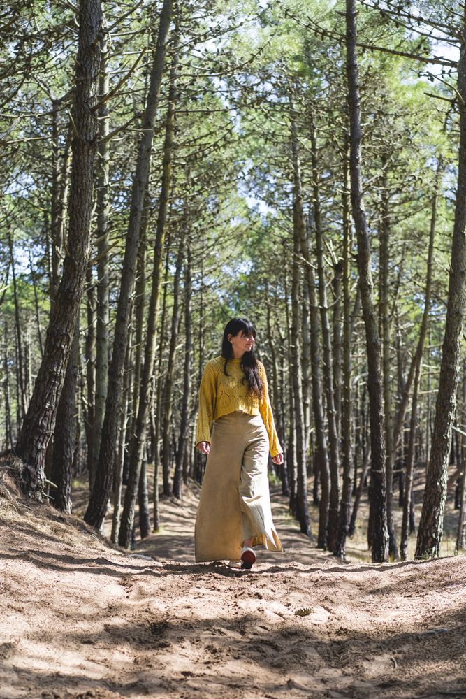 Adult woman walking over a path under the trees in the forest. Vertical shot.