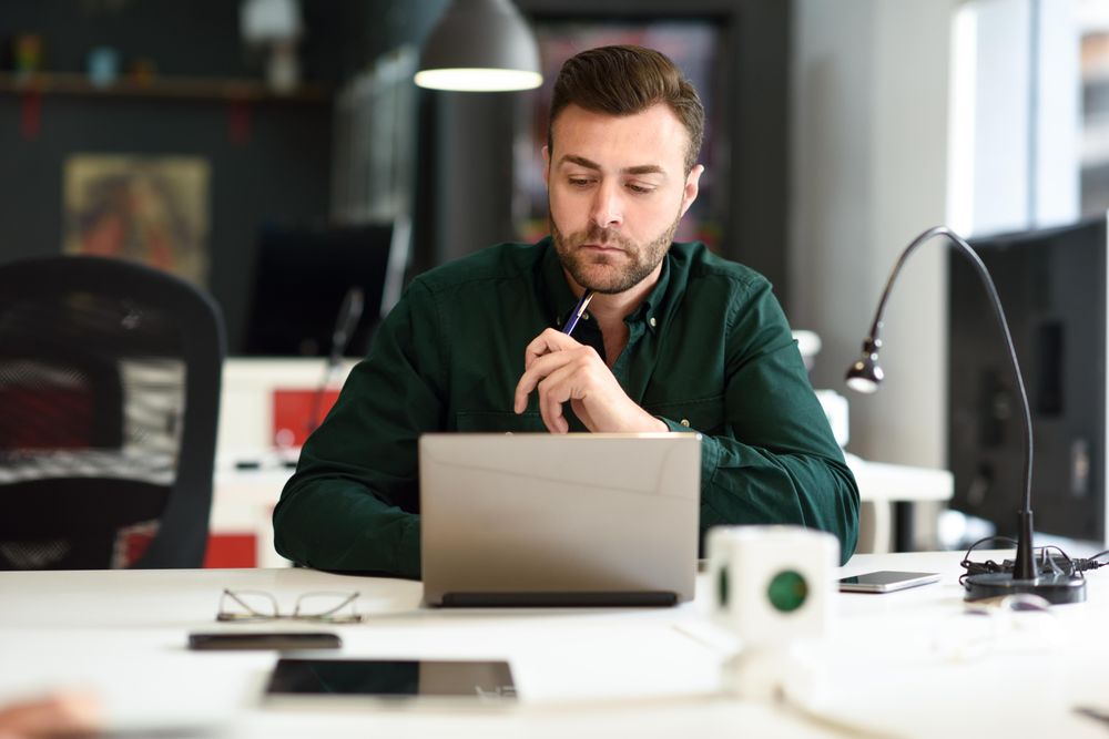 Young male studying with laptop computer in modern office