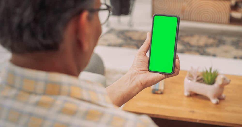 Over the Shoulder Mature Man Using Smartphone with Green Chroma key Screen