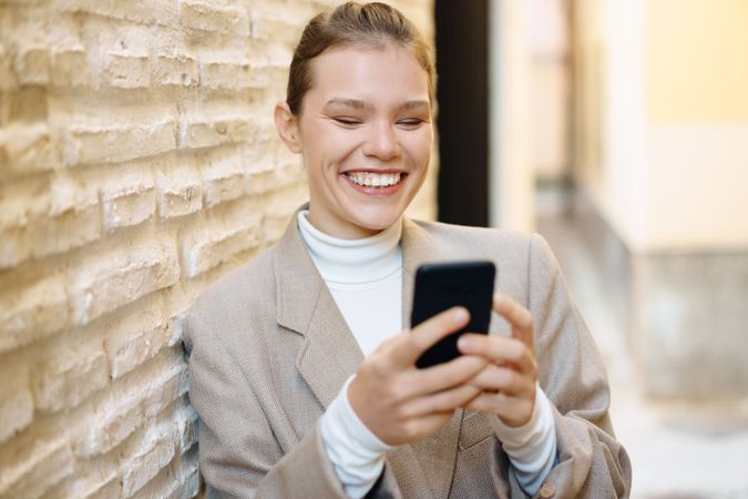 A Joyful Young Woman is Engaged with Her Smartphone While in a Modern Urban Setting Today