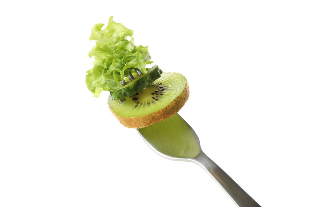 Fork with salad, cucumber and kiwi isolated on blank background