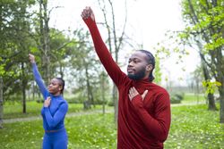Two young fit people warming up together before starting their workout.