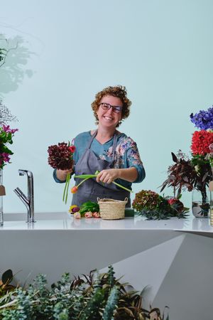 Smiling mature woman with flowers in floral store