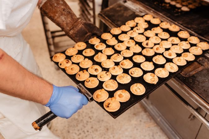 Bald baker checking pastry inside oven