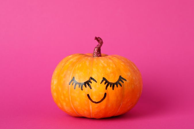 Pumpkin with smile on pink background, space for text