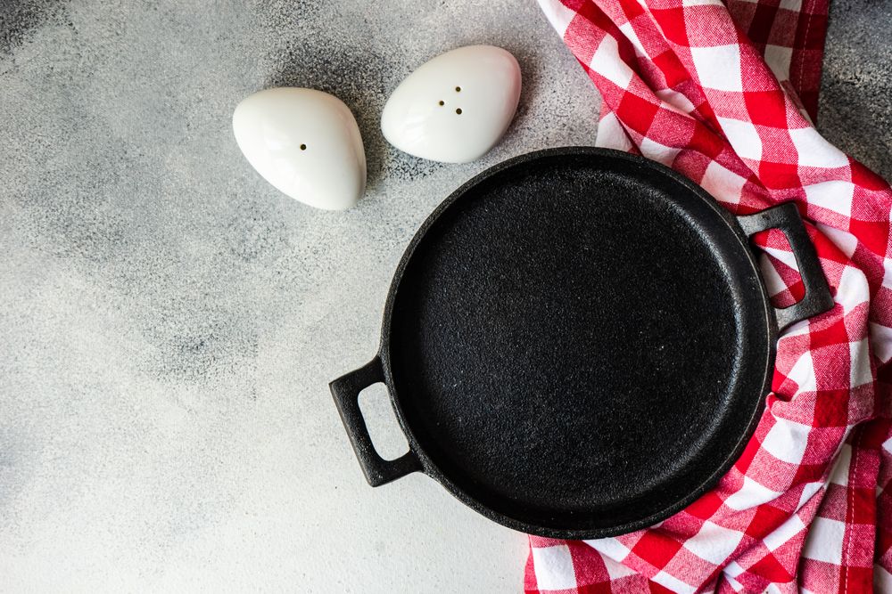 Empty iron cast pan with checkered red napkin with salt & pepper shakers