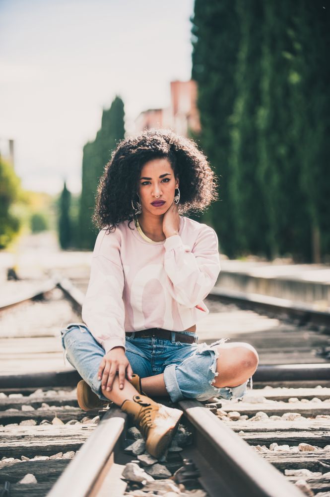 Black woman looking at camera in the tracks of a train