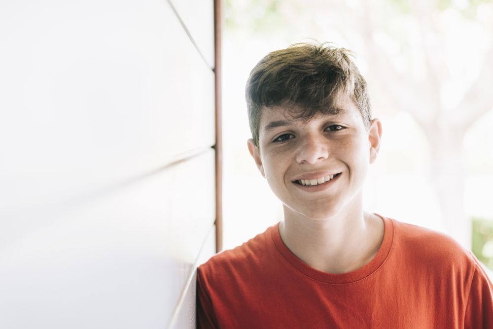 Portrait of a cheerful male teen outside in sunny yard with copy space
