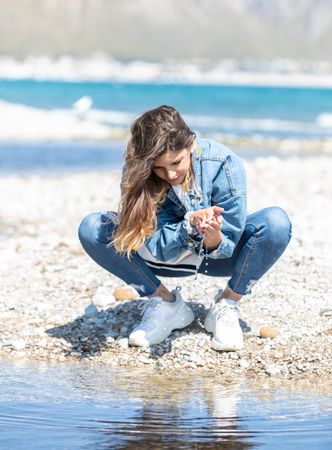 Young woman playing with water on shore