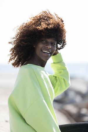 Vertical portrait of smiling female with curly hair in bright green shirt
