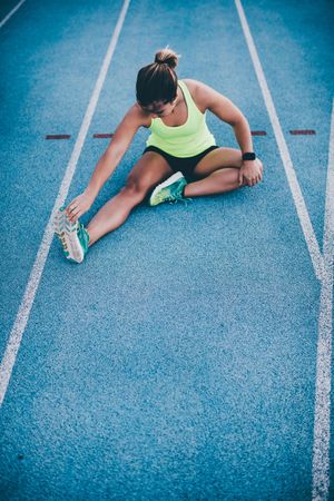 Young woman stretching in a land on a track field