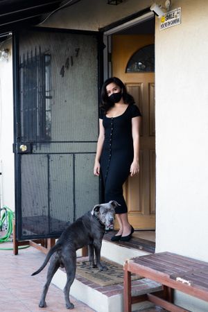 Full length Covid front door portrait of woman standing with her dog
