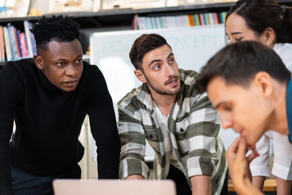 Diverse colleagues leaning over desk working on project