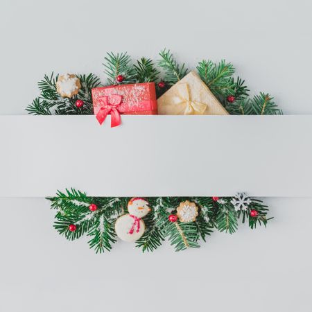 Christmas tree branches with decorations and cookies, behind gray paper