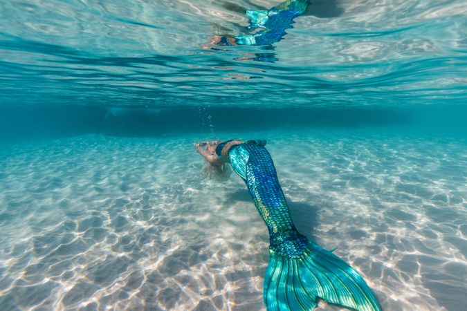 Blond fairytale female mermaid swimming underwater