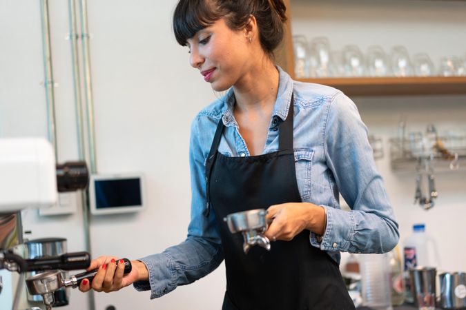 Woman making espresso at machine in cafe