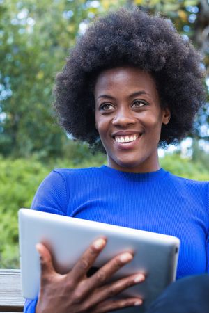 Smiling Black woman browsing tablet in city