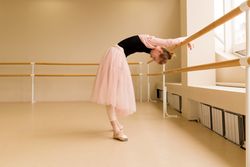 Ballet dancer arching backward at barre