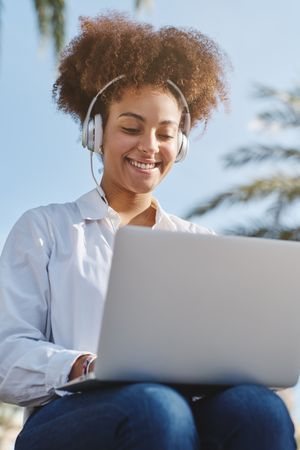 Smiling Black woman browsing laptop on street
