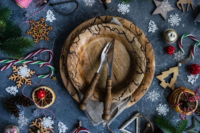 Rustic table setting surrounded by Christmas ornaments, candy canes and fir scattered on marble table