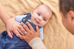 Young  Couple Laying With Their Infant On A Blanket