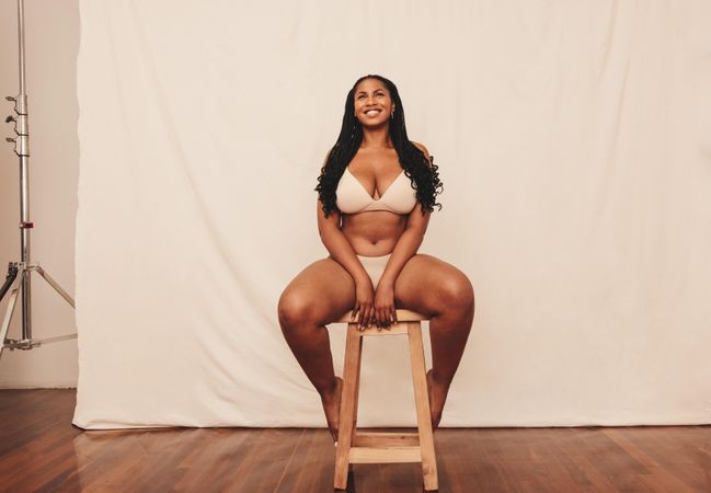 Confident Black model sitting on stool in studio
