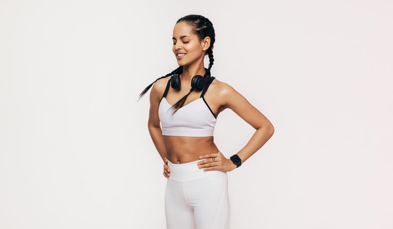 Woman in sports gear smiling with headphones around her neck