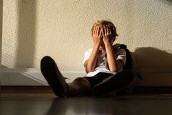 Lonely pupil covering face in classroom