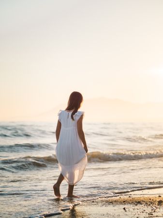 Adorable girl walking on seaside at sunset