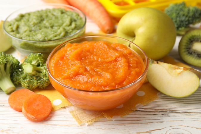Composition with baby food on plain wooden background