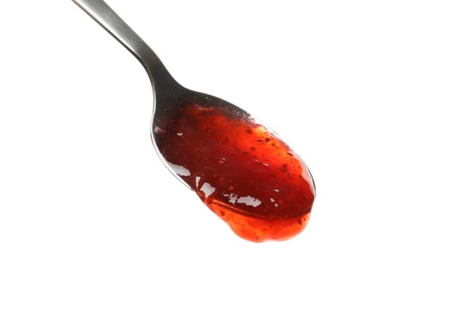 Spoon with strawberry jam isolated on plain background