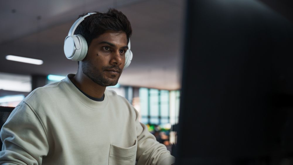 Portrait of a Stylish Indian Man Working on Desktop Computer in a Company Office.
