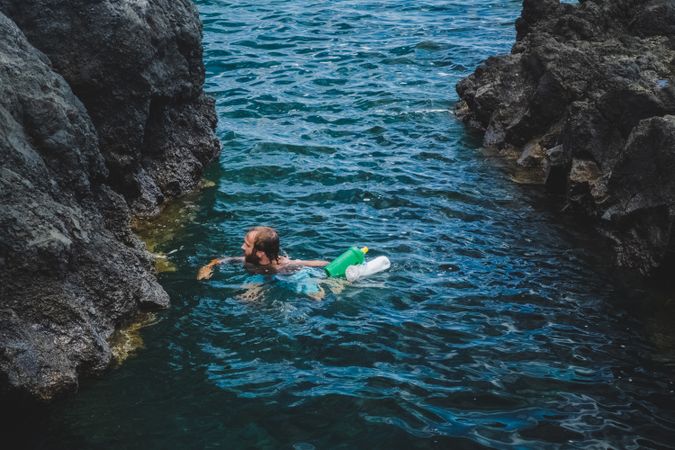Man swimming in water with rubbish