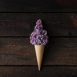 Ice cream cone with purple lilac on wooden background