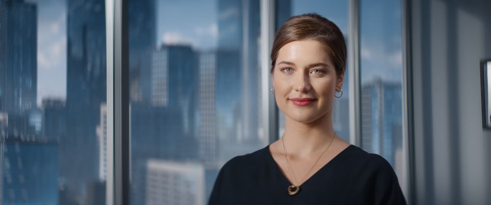 Close Up Portrait of White Businesswoman Posing Next to Window in Big City Office with Skyscrapers.