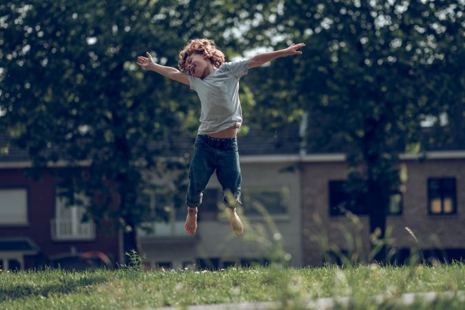 Cheerful boy jumping in meadow in countryside
