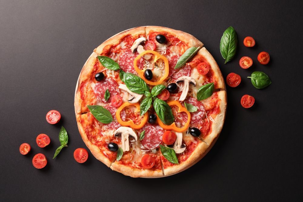 Delicious pizza and tomatoes on dark background, copy space