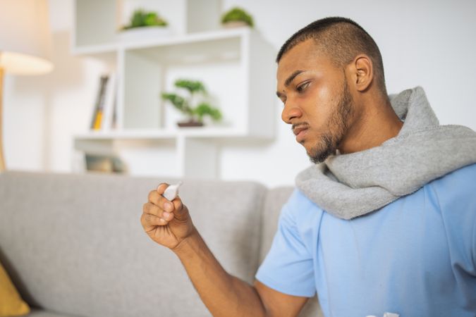 Young man with coronavirus taking his temperature