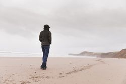 Man walking on sand shore near water