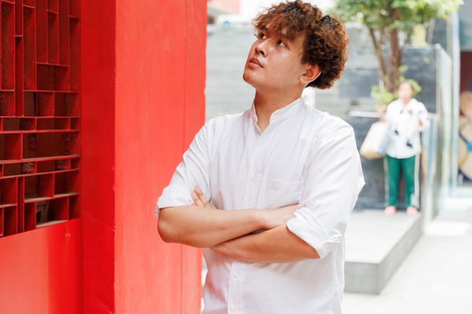 Portrait of Asian male in button up shirt standing with arms crossed