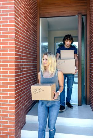 Couple moving carrying cardboard boxes