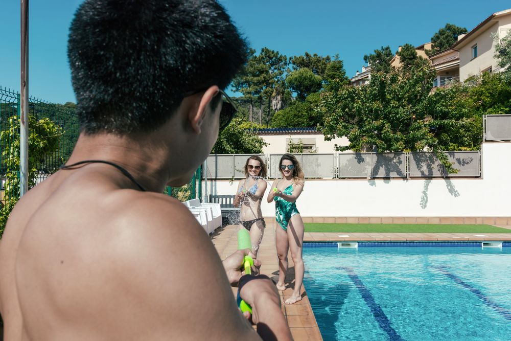 Friends playing with water pistols in the pool