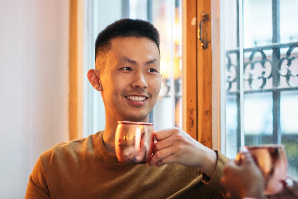 Asian man having a drink in an indoor space