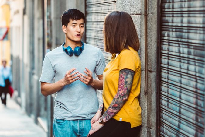 Joyful multiracial friends talking while standing on city street