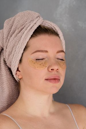 Applying eye patches in skincare routine.
