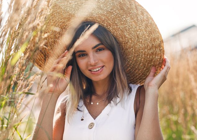 Portrait of woman in field wearing a large straw hat