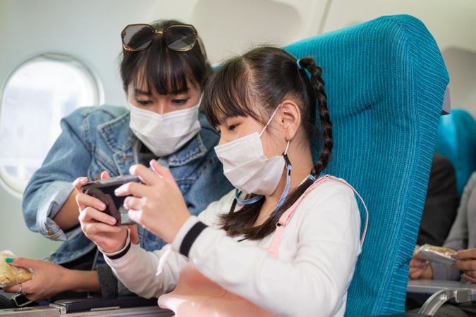 Mother and child checking phone together in airplane