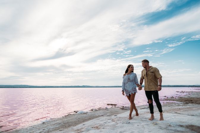 adorable couple walking on an amazing beach with pink water
